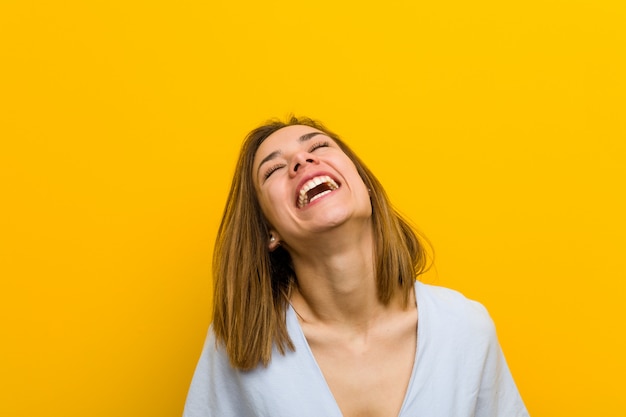 Foto joven bastante joven relajada y feliz riendo, cuello estirado mostrando los dientes.