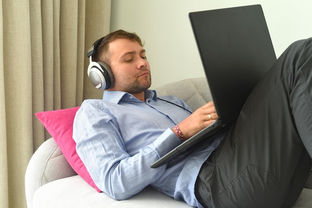 Un joven beat maker trabajando desde casa con su laptop en el sofá