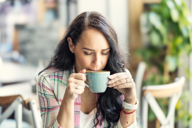 Una joven bebe capuchino en una cafetería.