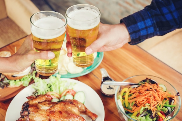 Joven bebiendo cerveza y tintineo de vasos