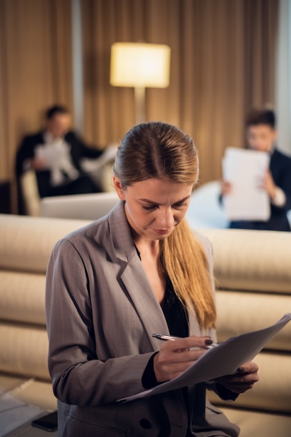 Una joven y bella empresaria pasando por su discurso en una habitación de hotel con su familia en la parte de atrás