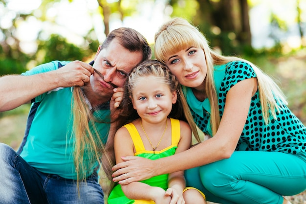 Foto joven y bella familia en el parque. madre, padre e hija