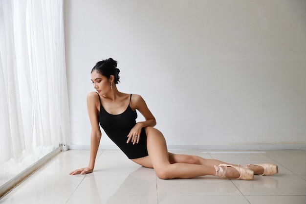 Joven y bella mujer asiática bailarina de ballet en estudio de pared blanca