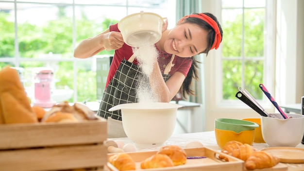 Una joven y bella mujer asiática está horneando en su negocio de cocina, panadería y cafetería.