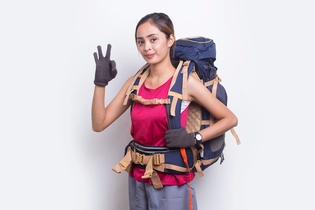 Joven y bella mujer asiática excursionista con mochila mostrando un pulgar hacia arriba gesto ok sobre fondo blanco.