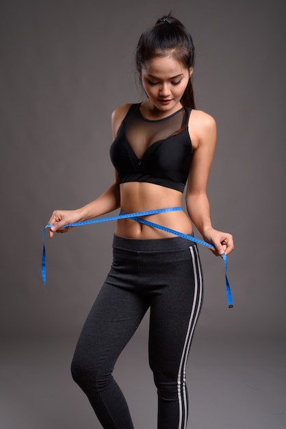 Joven y bella mujer asiática fitness con cintura delgada con cinta métrica