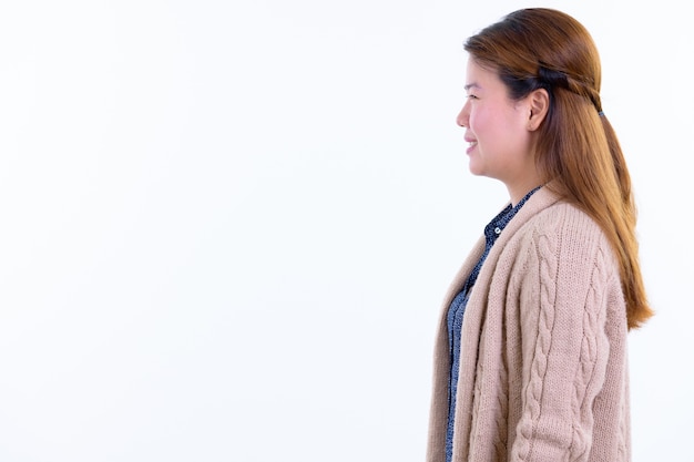 Joven y bella mujer asiática lista para el invierno aislado contra la pared blanca