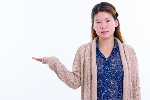 Joven y bella mujer asiática lista para el invierno aislado contra la pared blanca