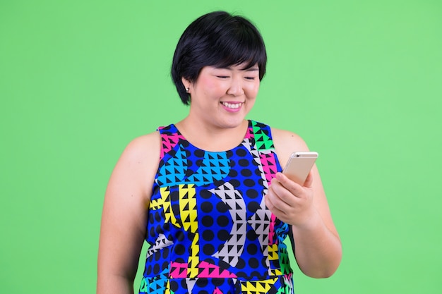 Joven y bella mujer asiática con sobrepeso lista para la fiesta contra chroma key con pared verde