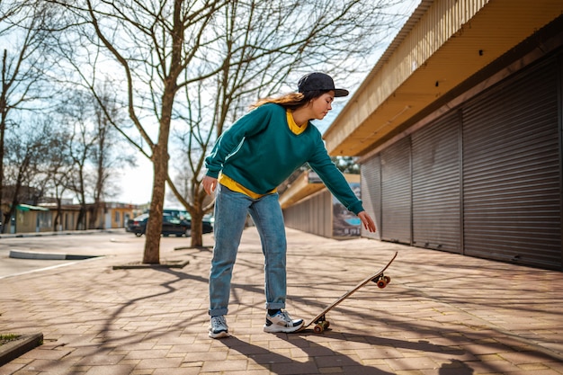 Una joven y bella mujer caucásica se inclina para andar en patineta