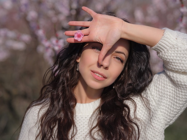 Una joven y bella mujer cerca de un árbol de cerezos en flor de primavera en flor. La idea y el concepto de renovación, autocuidado, salud y felicidad, al estilo japonés.