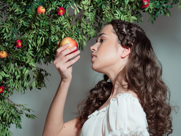 Una joven y bella mujer en el jardín del Edén prueba una fruta madura