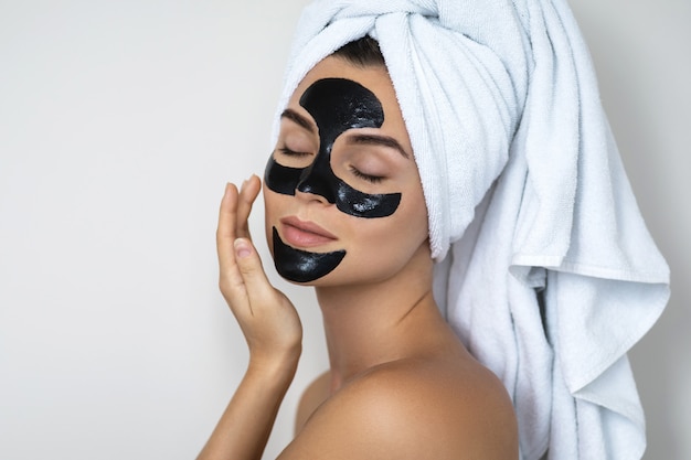 Foto joven y bella mujer con máscara negra desprendible en su rostro