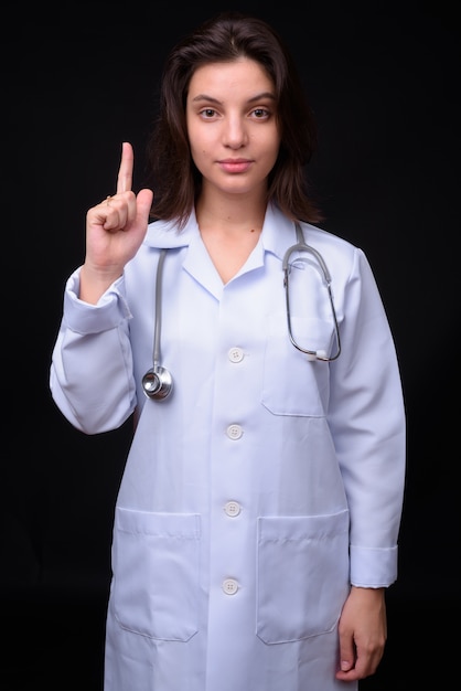 Joven y bella mujer médico contra la pared negra