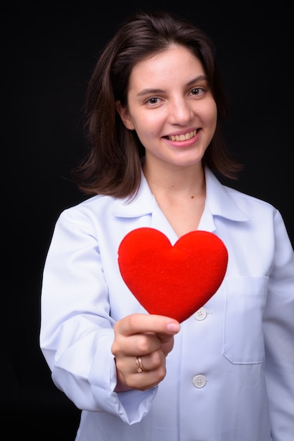 Foto joven y bella mujer médico contra la pared negra