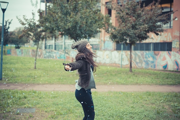 joven y bella mujer morena jugando con confeti carnaval