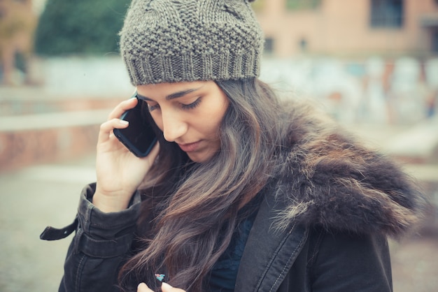 joven y bella mujer morena llamada con teléfono móvil