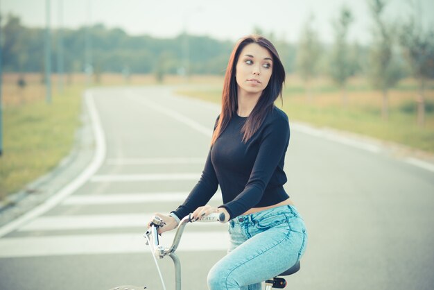 joven y bella mujer morena de pelo lacio con bicicleta