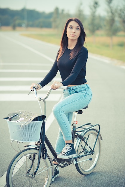 Foto joven y bella mujer morena de pelo lacio con bicicleta