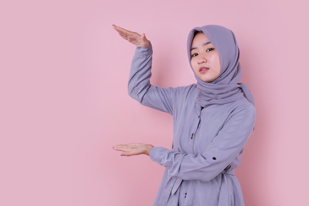 Una joven y bella mujer musulmana mostrando un objeto invisible