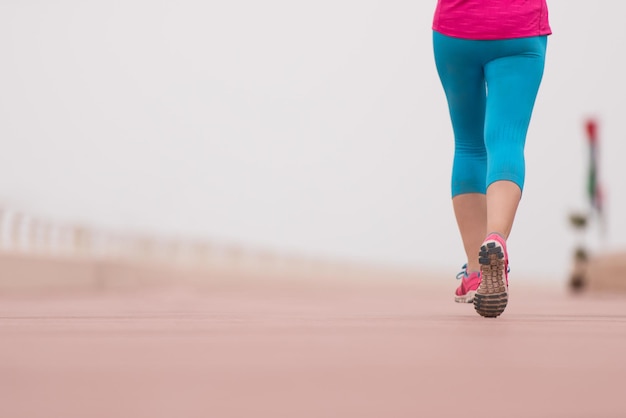 Foto joven y bella mujer muy activa ocupada corriendo en el paseo marítimo a lo largo del lado del océano para mantener sus niveles de condición física tanto como sea posible