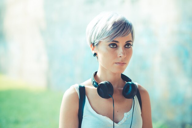 joven y bella mujer de pelo corto azul hipster con música de auriculares