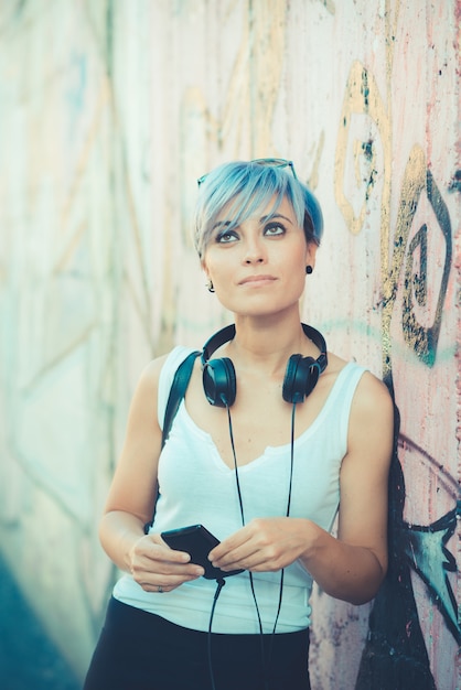 joven y bella mujer de pelo corto azul hipster con música de auriculares