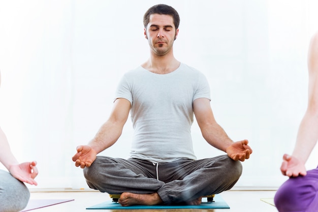 Joven y bella mujer practicando yoga en casa. Sukhasana plantean.