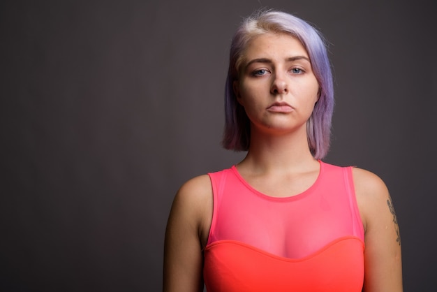 Joven y bella mujer rebelde con cabello colorido vistiendo un vestido rojo neón