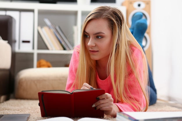 Joven y bella mujer rubia se encuentran en el piso leer libro