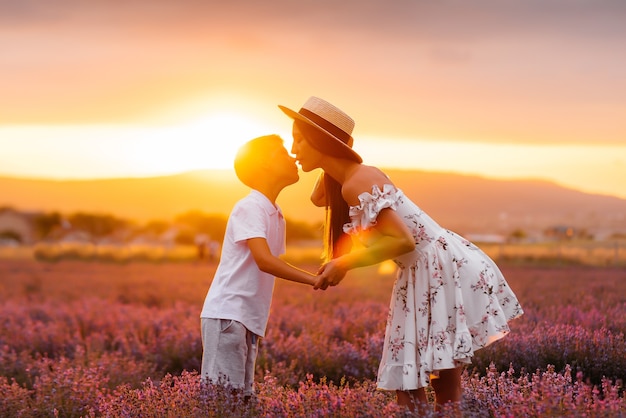 Una joven y bella mujer con su pequeño hijo camina por un hermoso campo de lavanda y disfruta de la fragancia de las flores. Descanso y hermosa naturaleza. Unidad con la naturaleza y armonía.