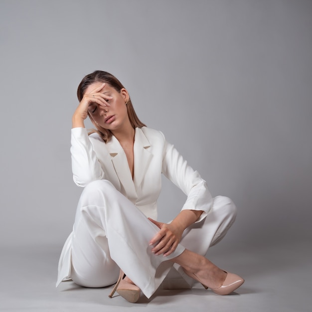 Una joven y bella mujer con un traje blanco de moda y zapatos de tacón beige