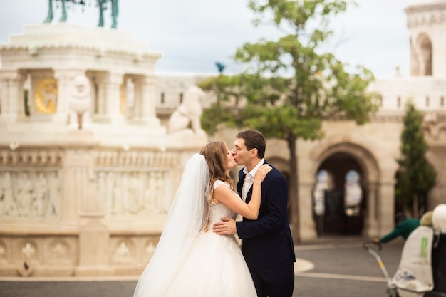 Joven y bella pareja elegante de recién casados caminando por el Bastión de los Pescadores en Budapest, Hungría