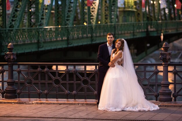 Joven y bella pareja elegante de recién casados cerca del río en Budapest