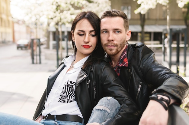 Joven y bella pareja de enamorados vistiendo chaquetas de cuero durante una cita en una calle de la ciudad