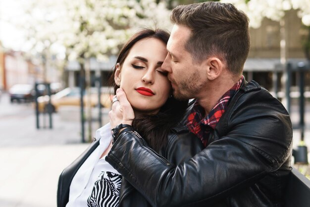Joven y bella pareja de enamorados vistiendo chaquetas de cuero durante una cita en una calle de la ciudad