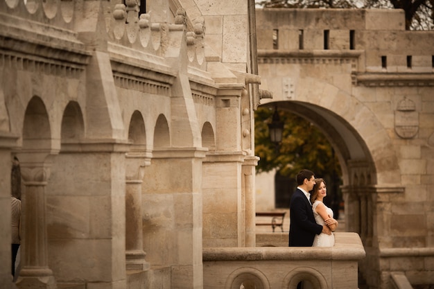 Joven y bella pareja de recién casados con estilo abrazando por el Bastión de los Pescadores en Budapest, Hungría