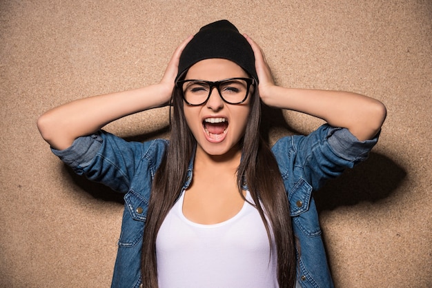 Joven belleza chica morena con gafas gritando.