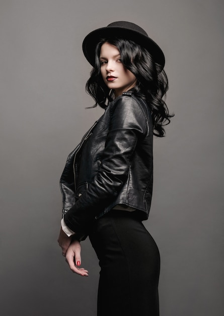 Joven belleza modelo de moda mujer con sombrero retrato en una pared gris