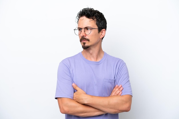 Joven con bigote aislado sobre fondo blanco manteniendo los brazos cruzados