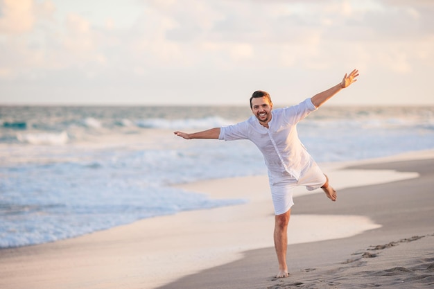 Joven de blanco en la playa divirtiéndose