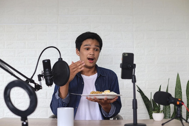 Joven blogger asiático de comida o vlogger mostrando y grabando un video en vivo de fideos