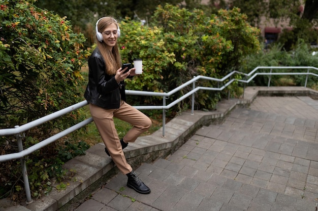 Joven bloguera escuchando música con auriculares en el parque