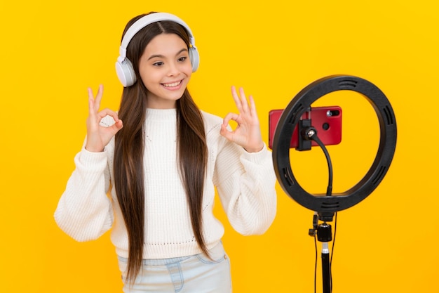 Una joven bloguera influyente usa una lámpara led selfie y un teléfono inteligente en un trípode para hacer videos en línea