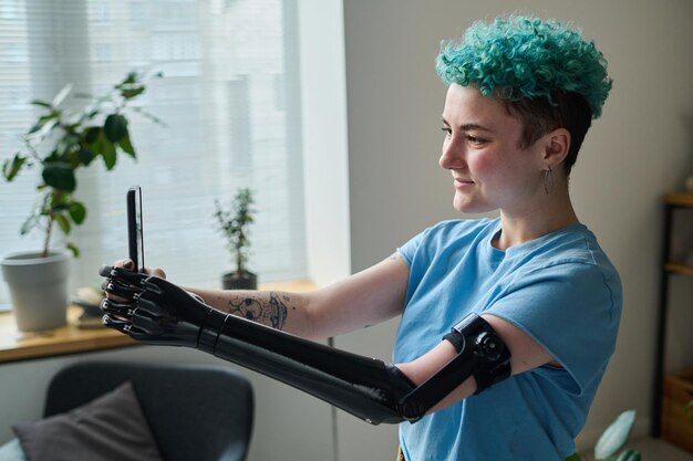 Joven bloguera con prótesis de brazo usando un teléfono inteligente para hablar con sus seguidores durante la transmisión en línea