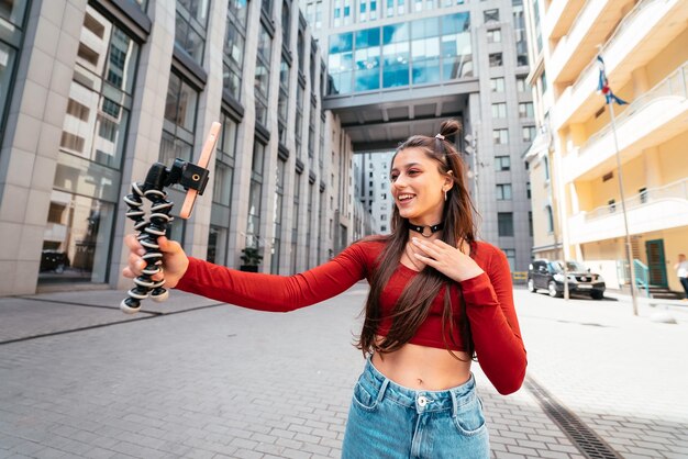 Joven bloguera con transmisión de teléfonos inteligentes en la calle