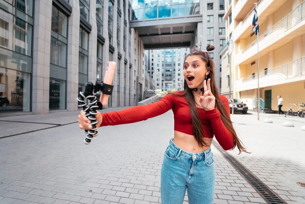 Joven bloguera con transmisión de teléfonos inteligentes en la calle