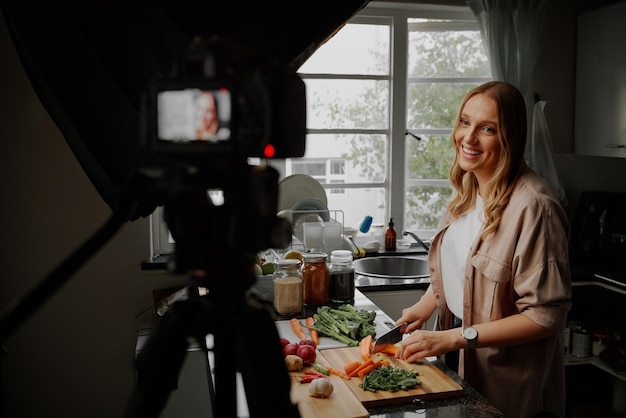 Joven bloguera vloguera e influenciadora en línea grabando contenido de video sobre comida saludable