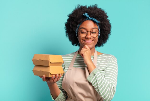 Joven bonita afro entregar a mujer con cajas de hamburguesas para llevar