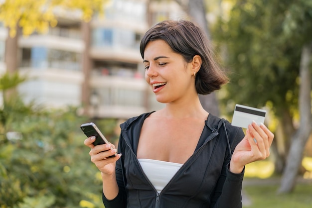 Foto joven bonita búlgara al aire libre comprando con el móvil con tarjeta de crédito